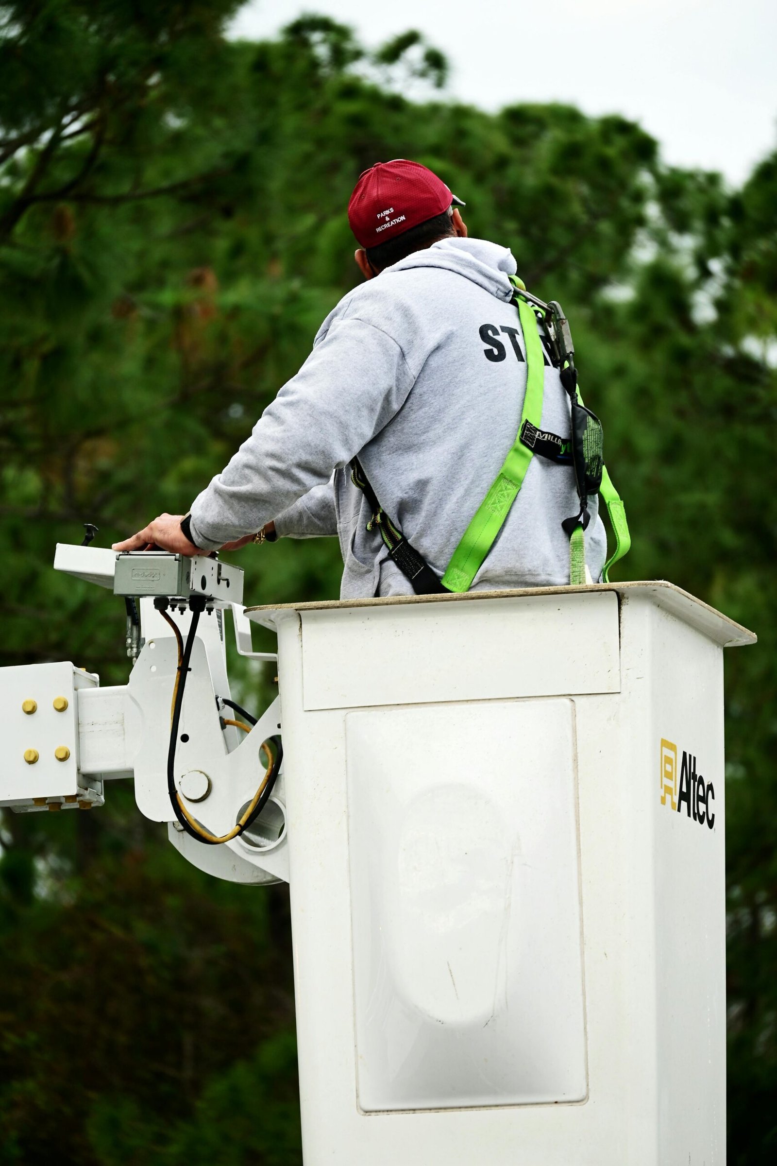 A worker wearing safety gear operates a bucket truck, focusing on safety and equipment handling.